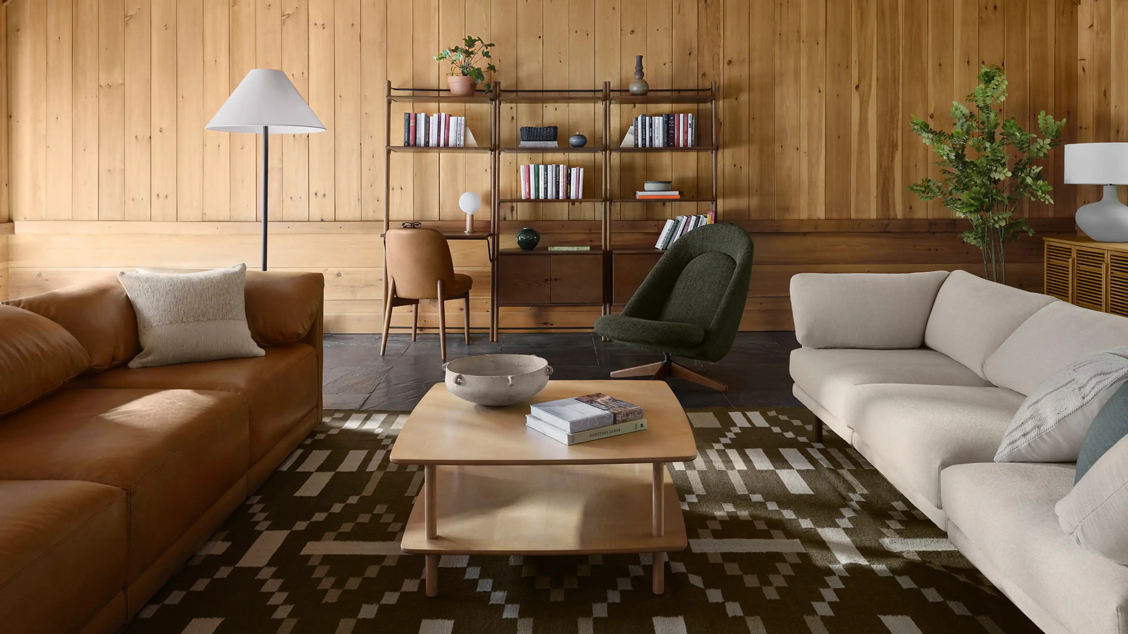 a living room with a brown leather couch, a brown coffee table, and a green armchair