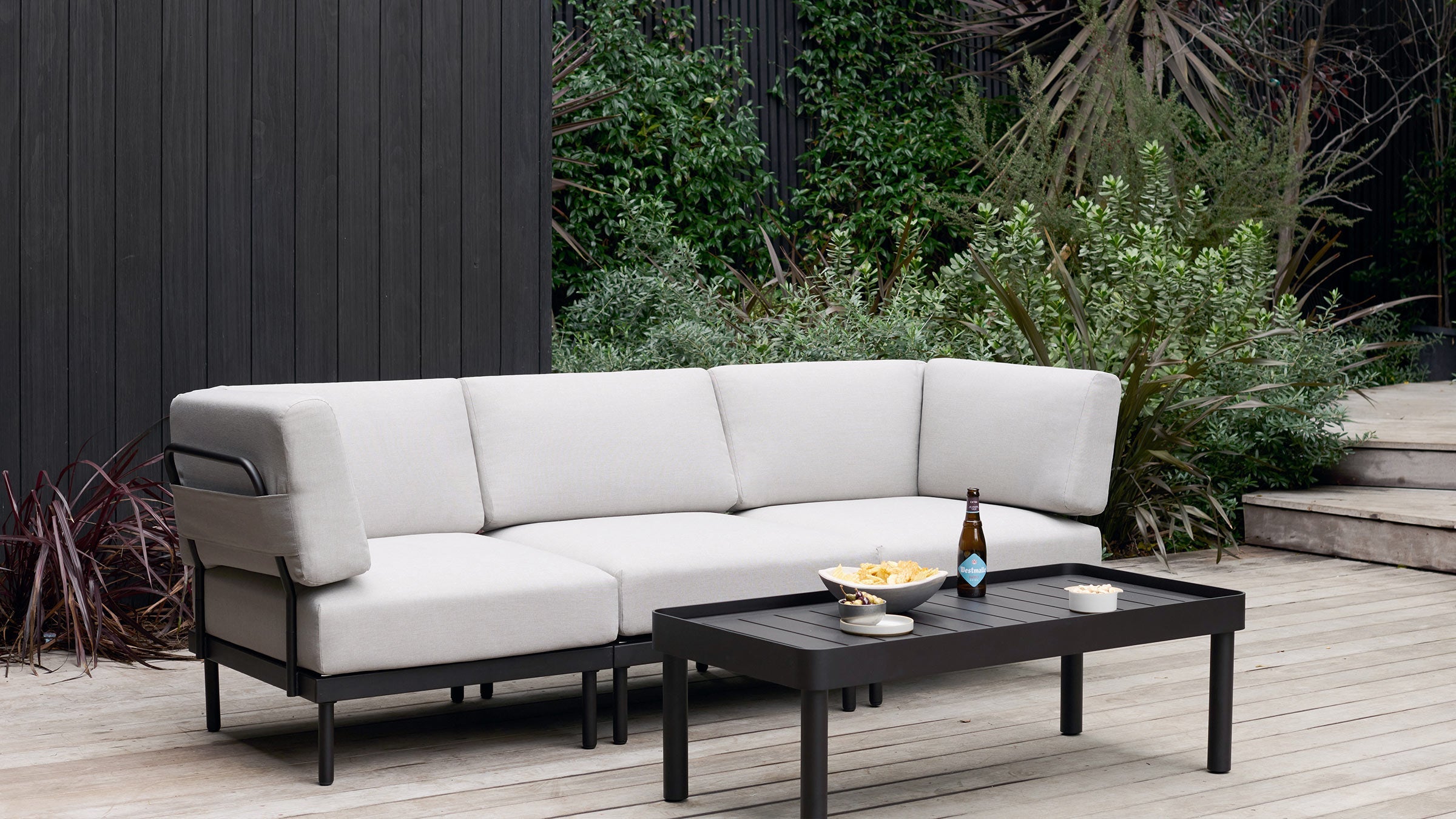 a modern outdoor sofa with a black coffee table on a wooden deck