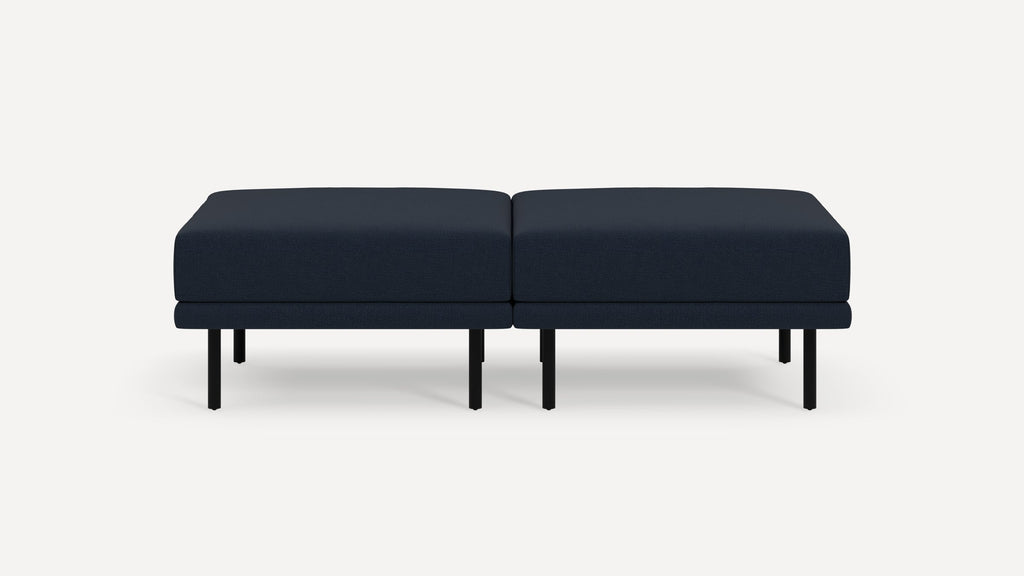 Modern navy blue fabric ottoman with black metal legs, designed as two side-by-side rectangular cushions.