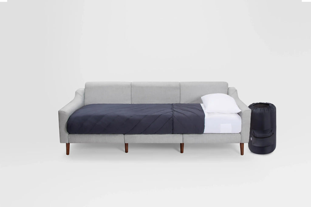 modern daybed with blue upholstery and white pillows, featuring a navy blue pillow, white pillow, and wooden legs