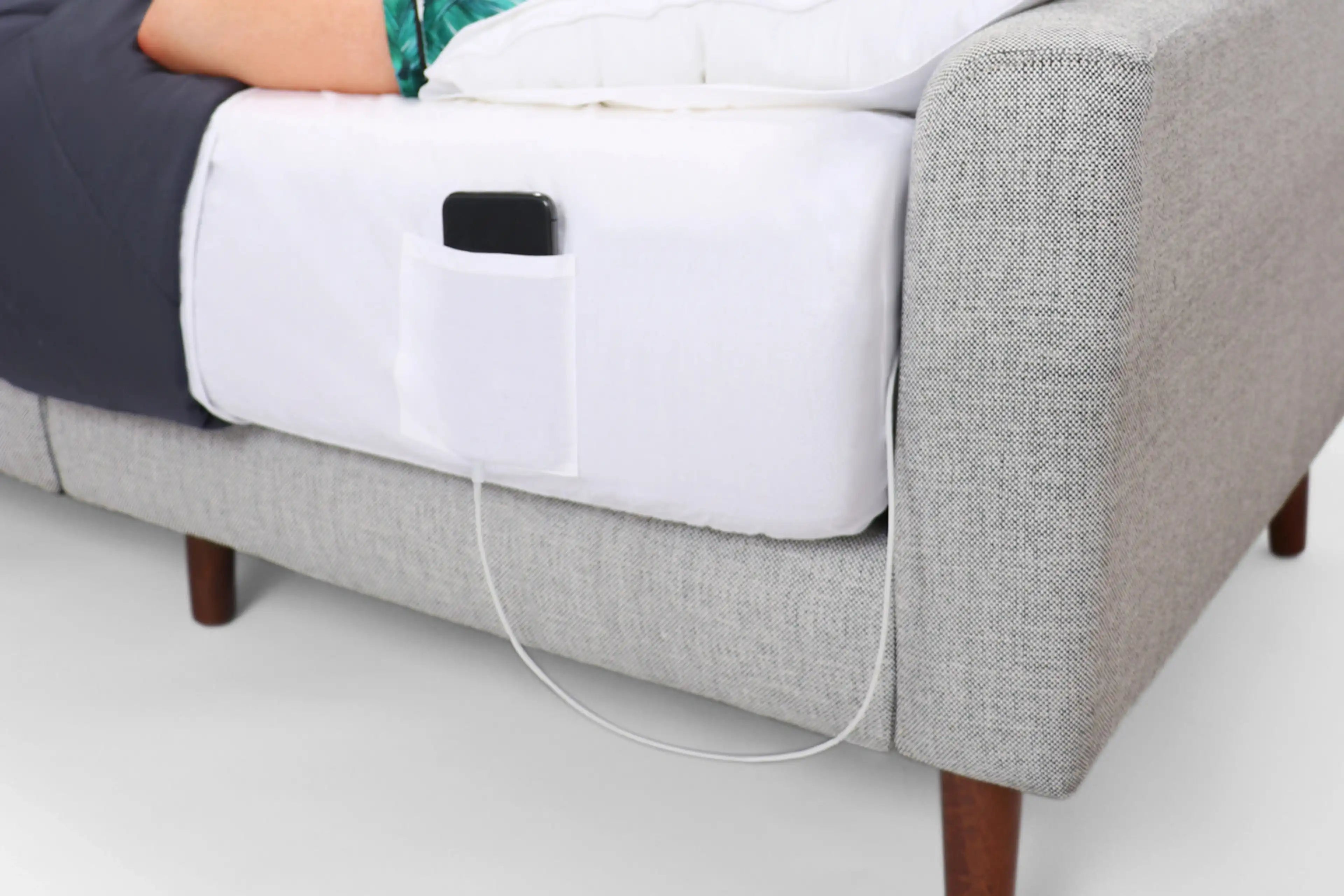 a person laying on a bed with a white pillow and a white phone