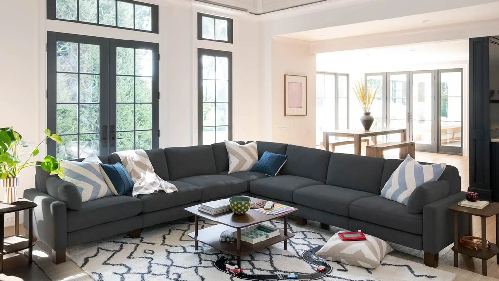 modern living room with gray sectional sofa, blue pillows, and a white rug on the floor