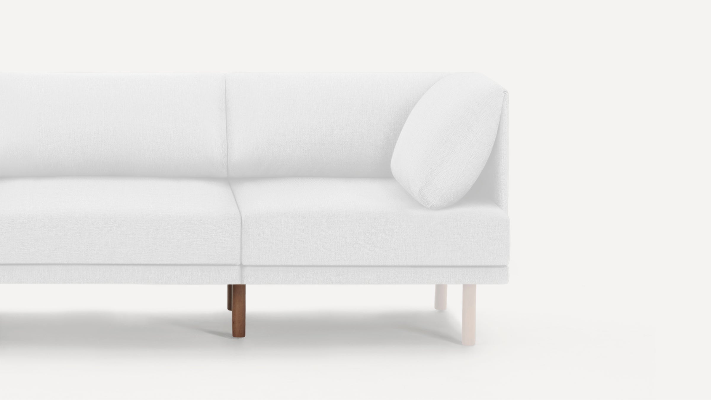 Modern white upholstered sectional sofa with clean lines, wooden legs, and a single matching cushion on the right side.