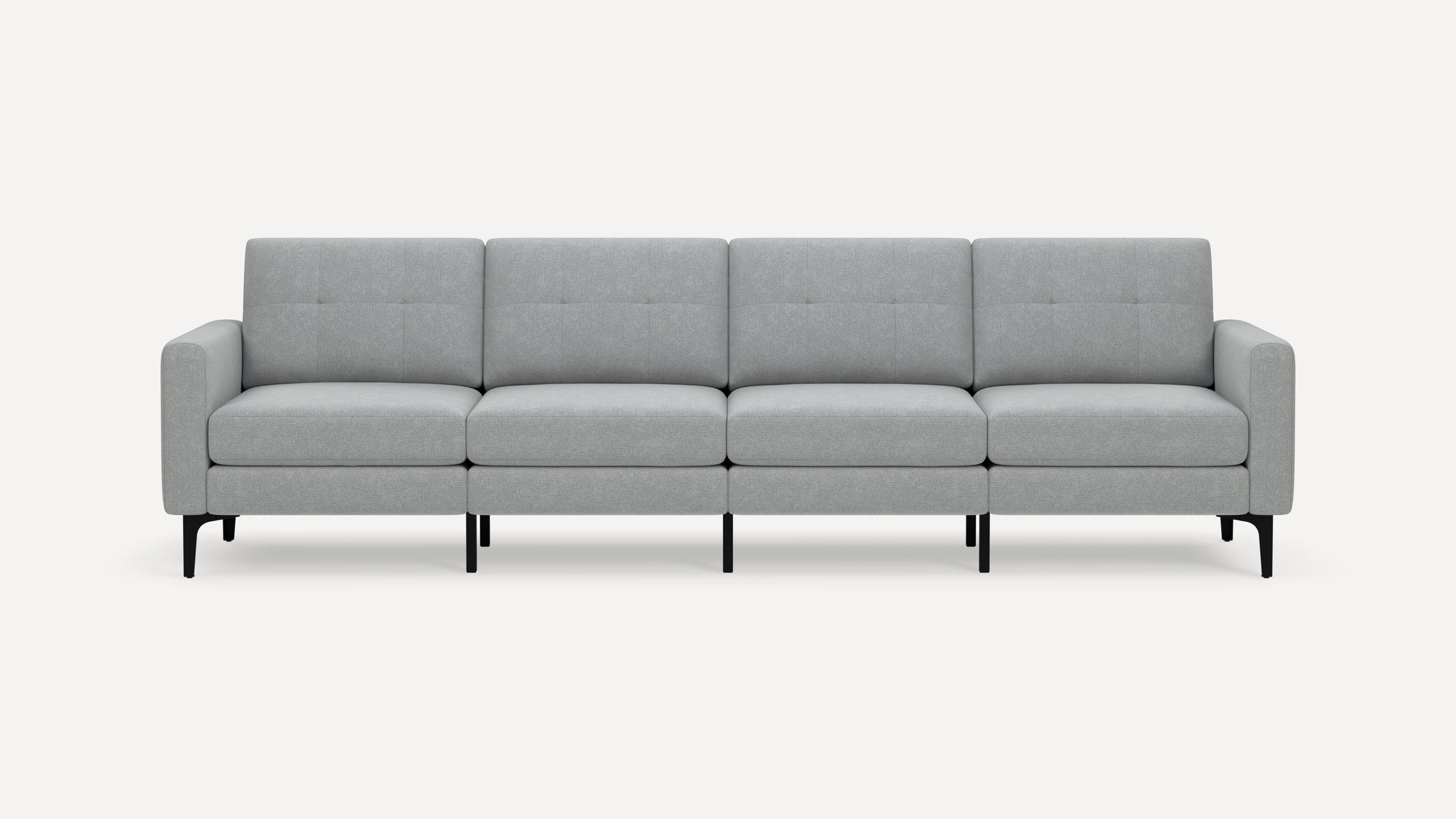 Modern light gray fabric four-seater sofa with clean lines, tufted back cushions, and black slim legs on white background.