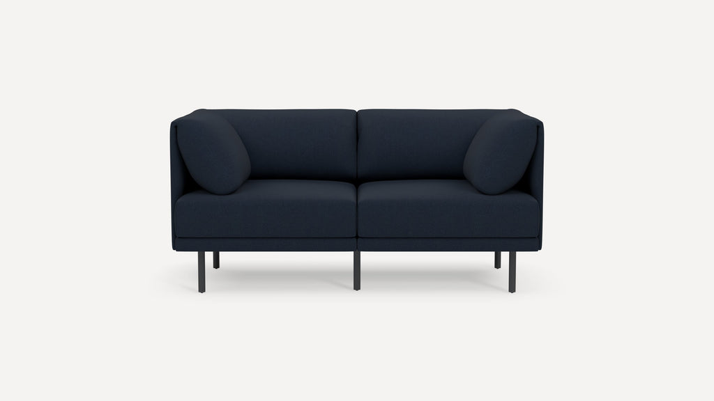 Modern navy blue two-seater sofa with rounded cushions and slim black metal legs, set against a plain white background.