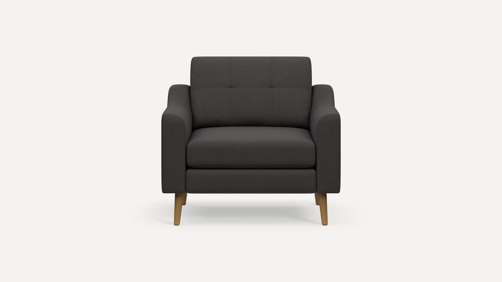 Dark gray upholstered armchair with tufted backrest, wide armrests, and light wooden tapered legs.