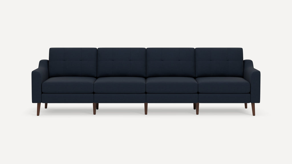 Modern four-seater navy blue fabric sofa with tufted back cushions and wooden tapered legs, set against a plain white background.