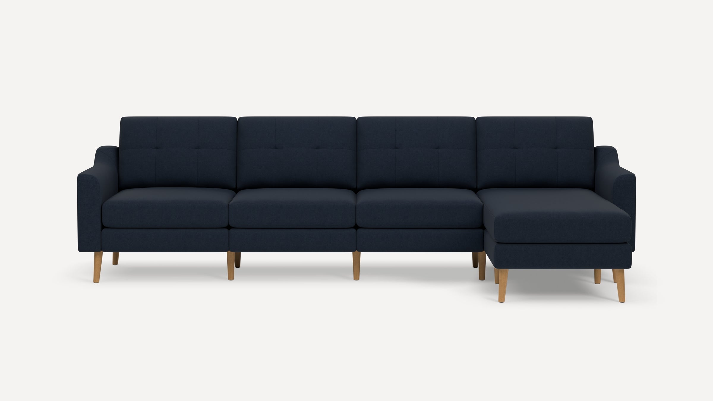 Modern navy blue sectional sofa with tufted cushions, wooden legs, and chaise lounge on the right side.