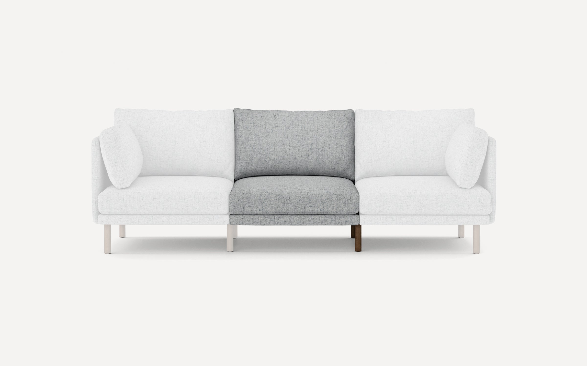 Three-seater sofa with white outer cushions and a central seat and back cushion in light gray fabric, supported by slender wooden legs.
