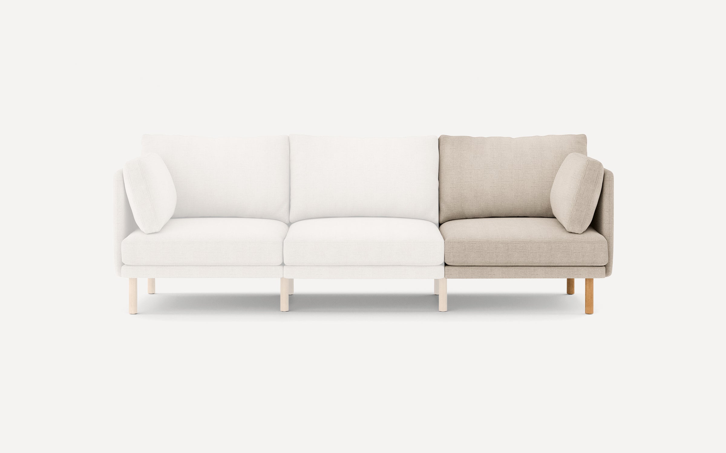 Modern three-seat sofa with light beige fabric upholstery, wooden legs, and loose back and side cushions against a plain white background.