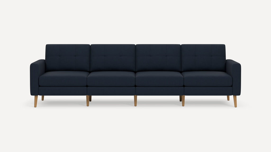 Modern navy blue four-seater sofa with tufted back cushions and wooden legs on a plain white background.