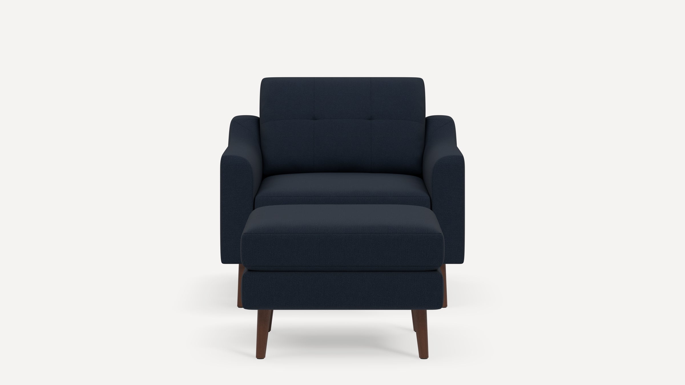 Front view of a modern navy blue armchair with matching ottoman and tapered wooden legs on white background.
