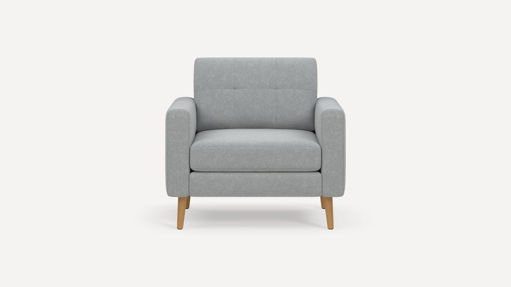 Light gray upholstered armchair with straight padded arms, tufted backrest, and wooden tapered legs on a white background.