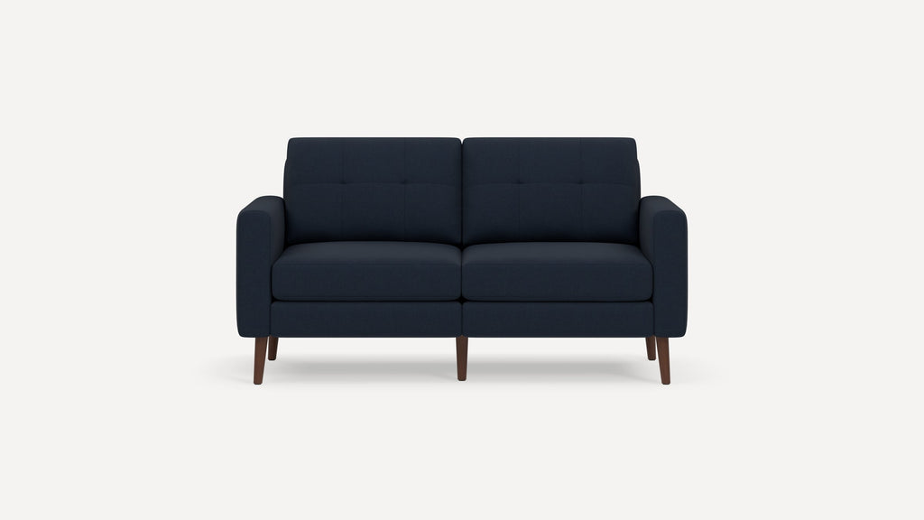 Modern two-seater navy blue fabric sofa with tufted back cushions, padded armrests, and wooden tapered legs on white background.