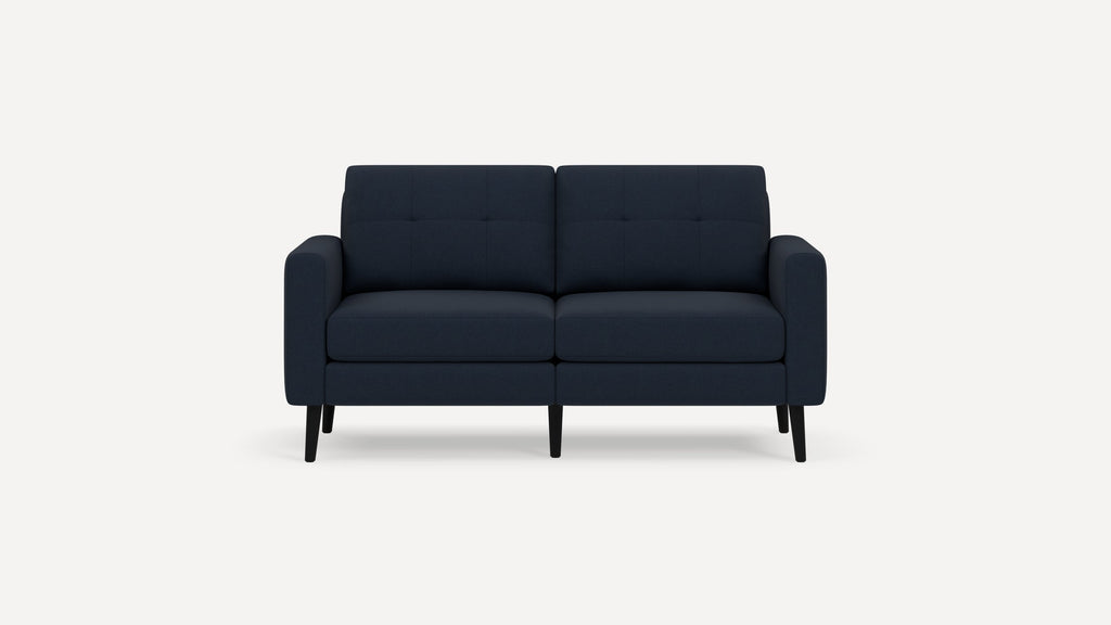 Modern two-seater sofa in dark blue fabric with tufted back cushions, rounded arms, and slim black wooden legs.