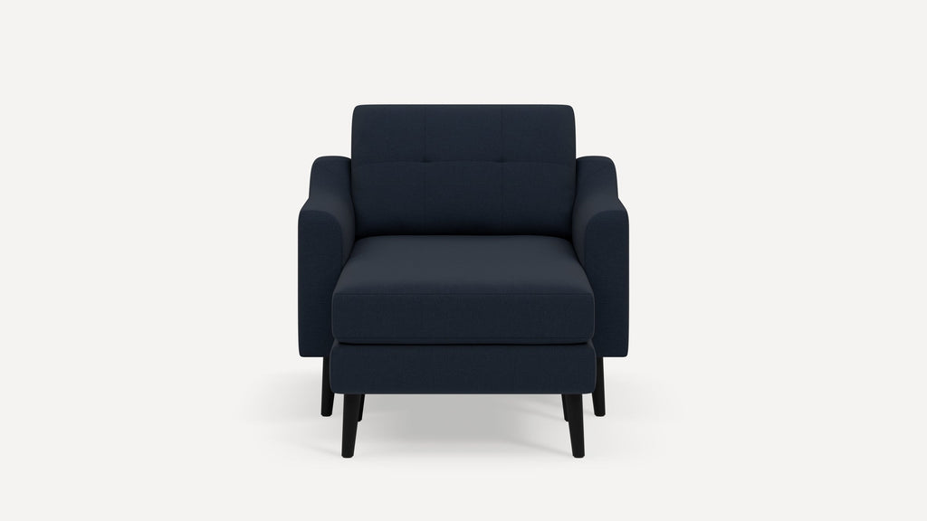 Modern navy blue armchair with matching ottoman, featuring clean lines, tufted backrest, and black wooden legs.