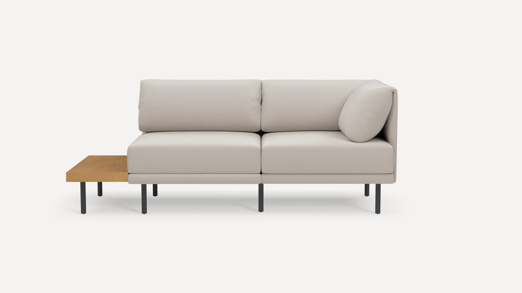 Modern beige sectional sofa with metal legs and attached wooden side table, minimalist design on white background.