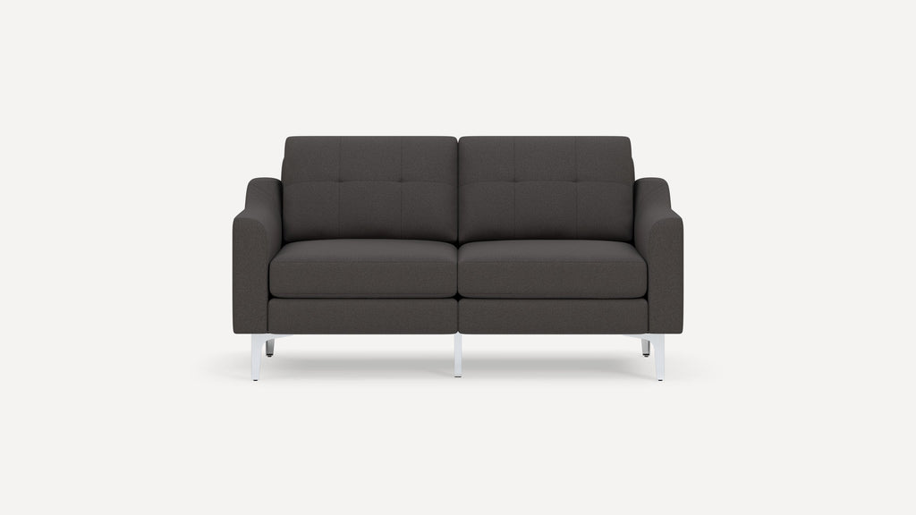 Modern dark gray upholstered two-seater sofa with tufted back cushions and sleek white metal legs on white background.