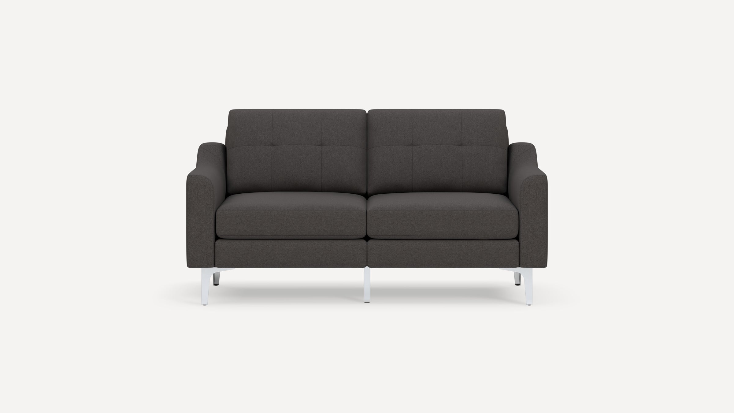Modern dark gray upholstered two-seater sofa with tufted back cushions and sleek white metal legs on white background.