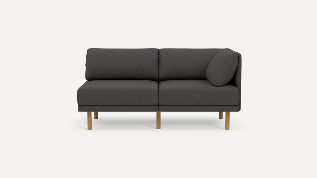 Modern dark gray two-seater sofa with wooden legs and a round side cushion on the right armrest.