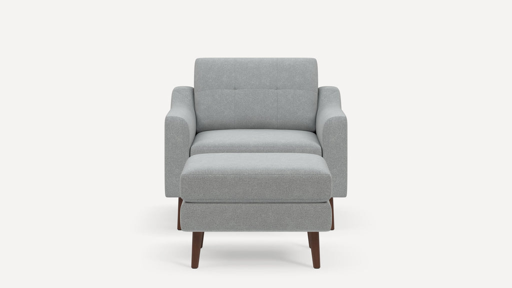 Front view of a modern light gray upholstered armchair with matching ottoman and wooden legs on a plain background.