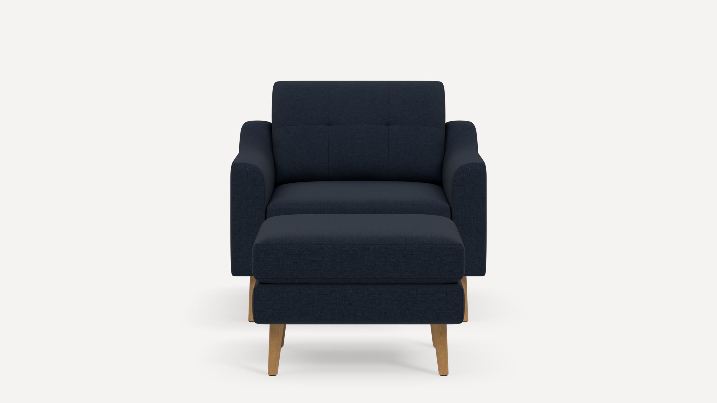 Modern navy blue fabric armchair with matching ottoman, featuring wooden legs and a tufted backrest against a white background.