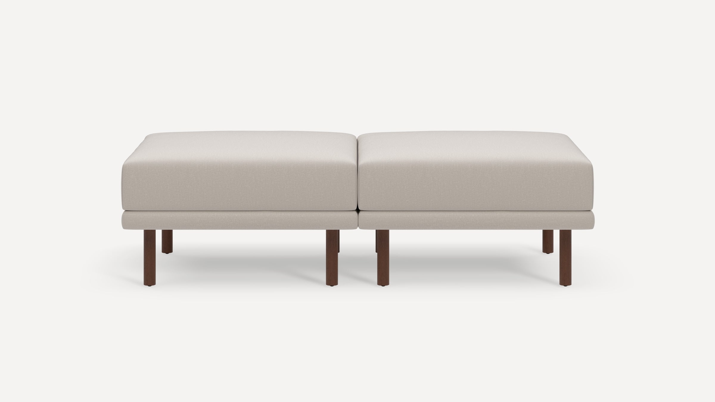 Two beige cushioned ottomans with simple rectangular shape, supported by dark wooden legs, placed side by side.