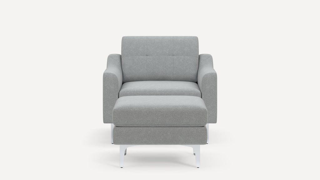 Front view of a modern light gray fabric armchair with matching ottoman and white metal legs on a white background.