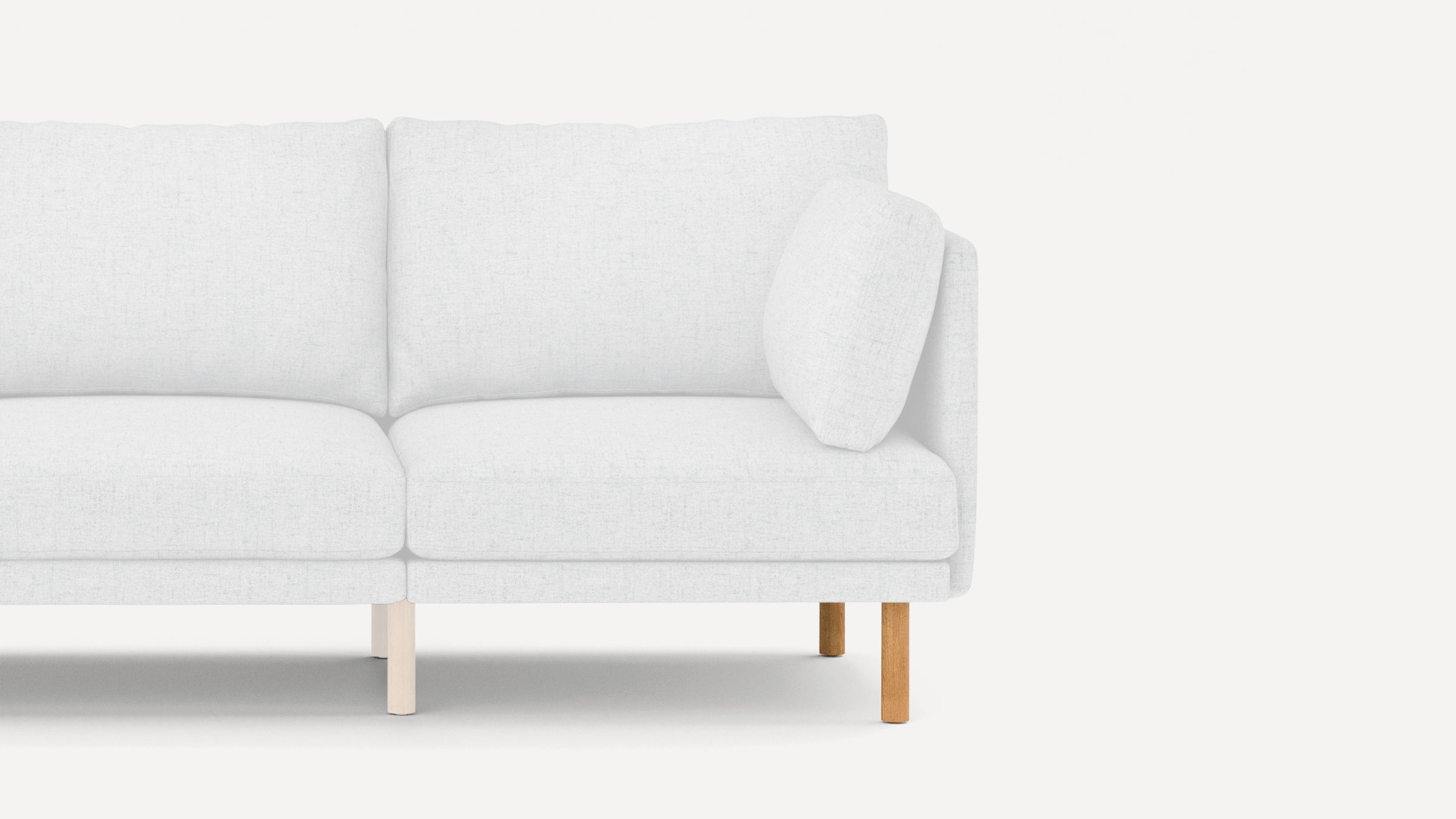 Partial view of a modern white fabric sofa with clean lines, featuring wooden legs and a matching white cushion on the right side.