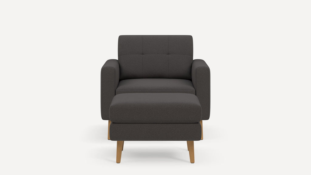 Front view of a modern dark gray armchair with matching rectangular ottoman and wooden legs on a white background.