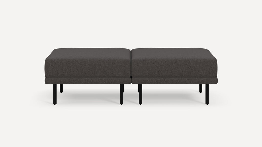 Modern dark gray upholstered rectangular ottoman with black metal legs, shown as two connected sections on a white background.