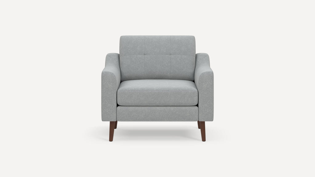 Front view of a modern light gray upholstered armchair with wooden tapered legs and padded armrests.