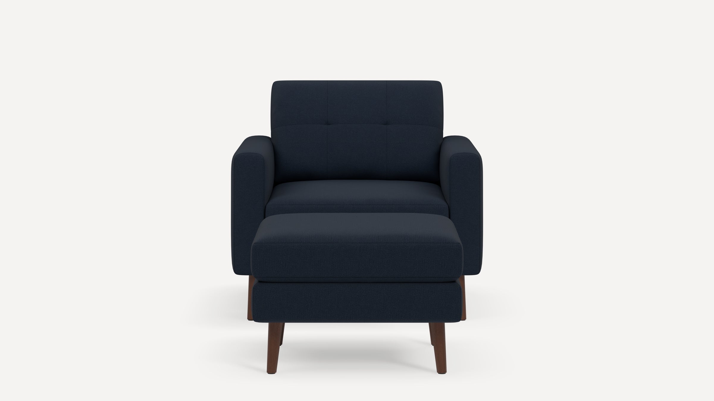 Front view of a modern navy blue armchair with matching ottoman, wooden legs, and padded cushions.