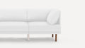 Minimalist white fabric modern sectional sofa corner with wooden legs and a loose cushion on a light background.