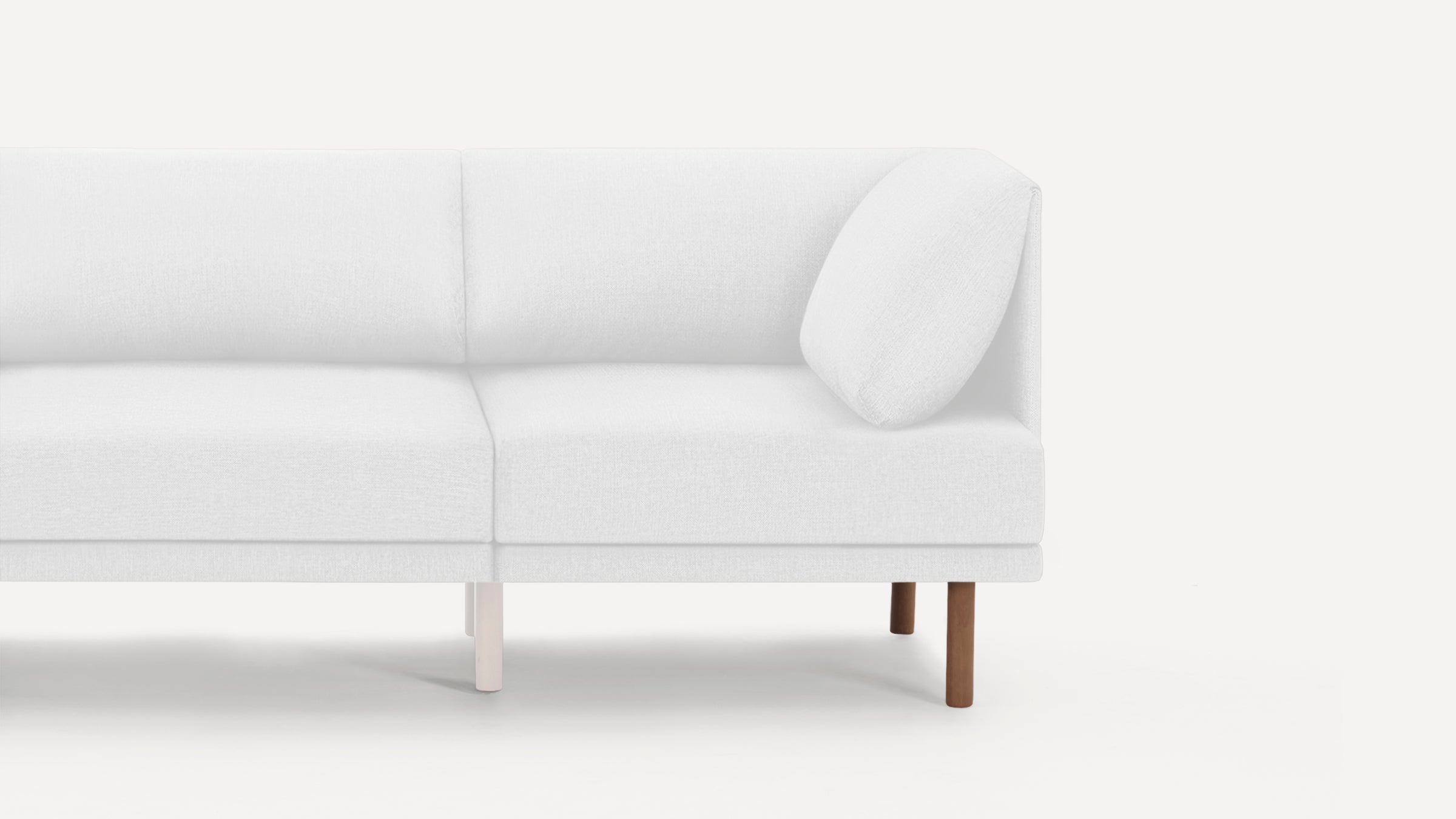 Minimalist white fabric modern sectional sofa corner with wooden legs and a loose cushion on a light background.