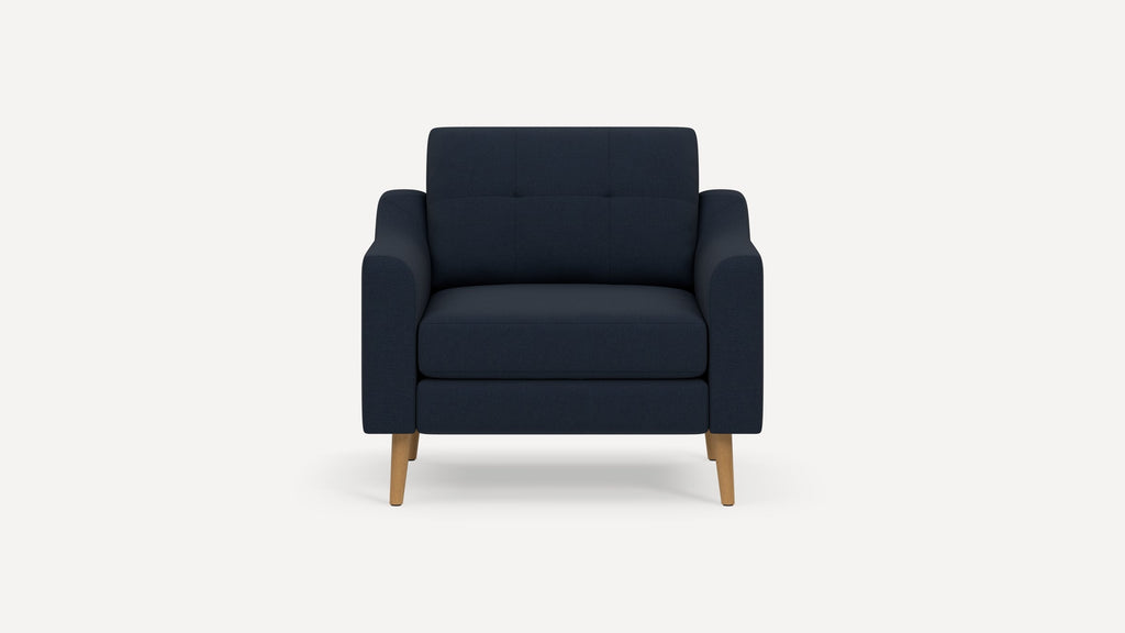 Modern navy blue upholstered armchair with wooden legs and tufted backrest, shown against plain white background.