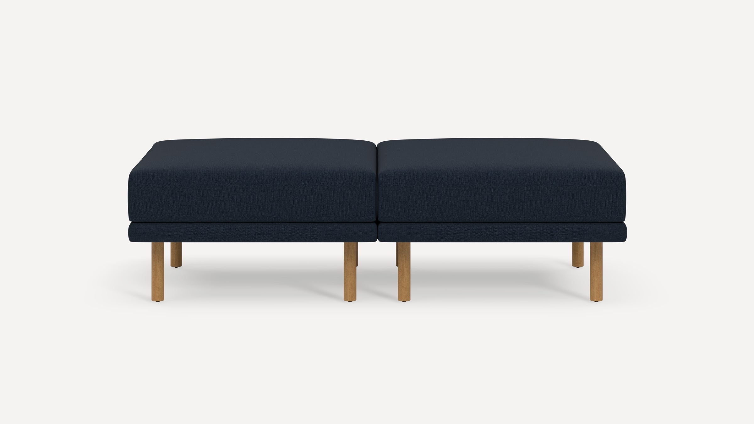 Modern navy blue upholstered double ottoman with natural wood legs, set against a plain light background.