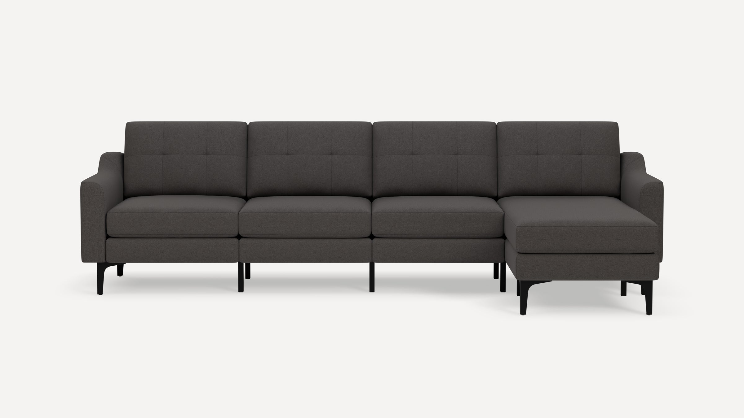 Dark gray modern sectional sofa with chaise lounge, tufted cushions, slim armrests, and black legs on white background.