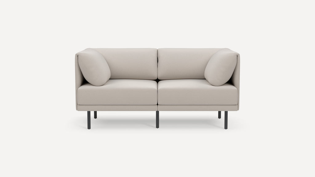 Modern two-seater beige sofa with clean lines, soft cushions, and slim black metal legs on a white background.