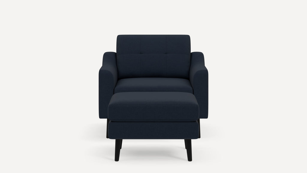 Front view of a modern dark blue upholstered armchair with matching ottoman, featuring black angled legs.