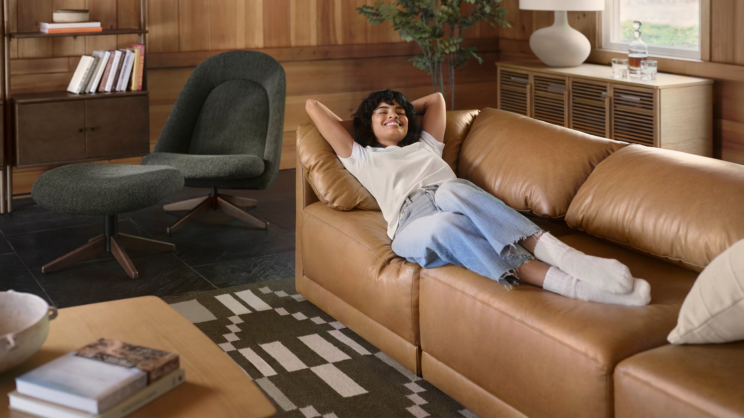 a woman laying on a brown leather couch in a living room