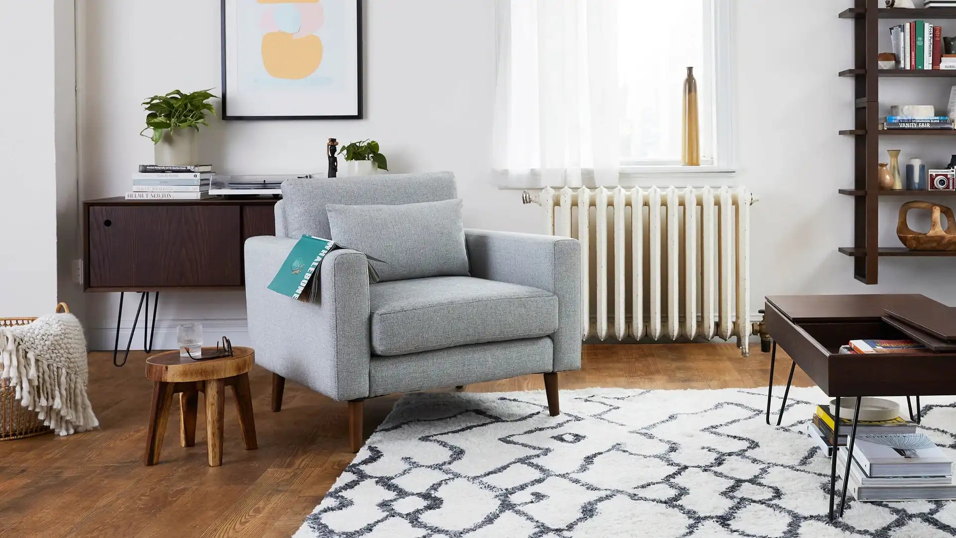 modern living room with gray armchair, white rug, wooden coffee table, and wooden side tables
