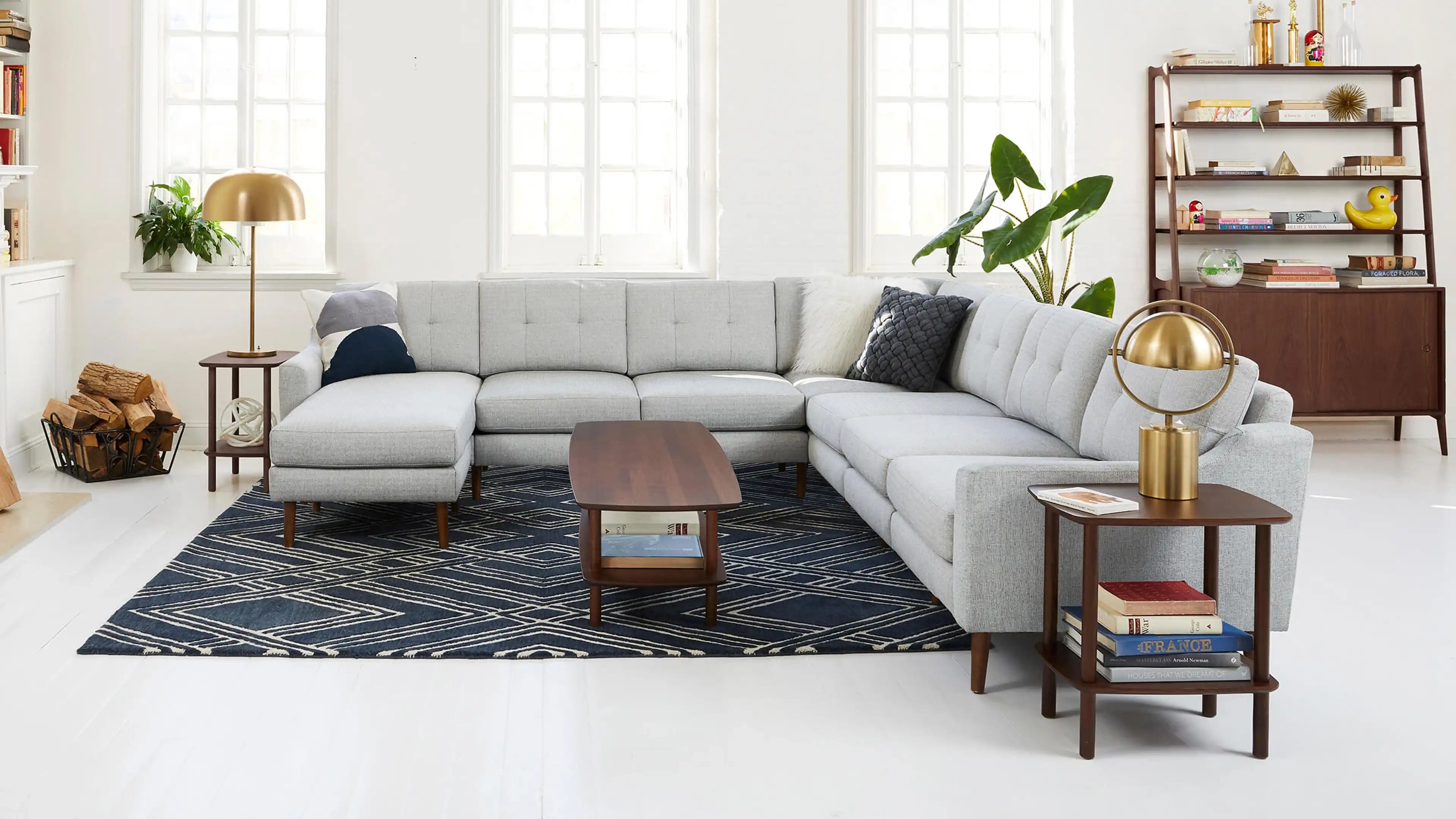 modern living room with light gray sectional sofa, wooden side tables, and blue patterned rug