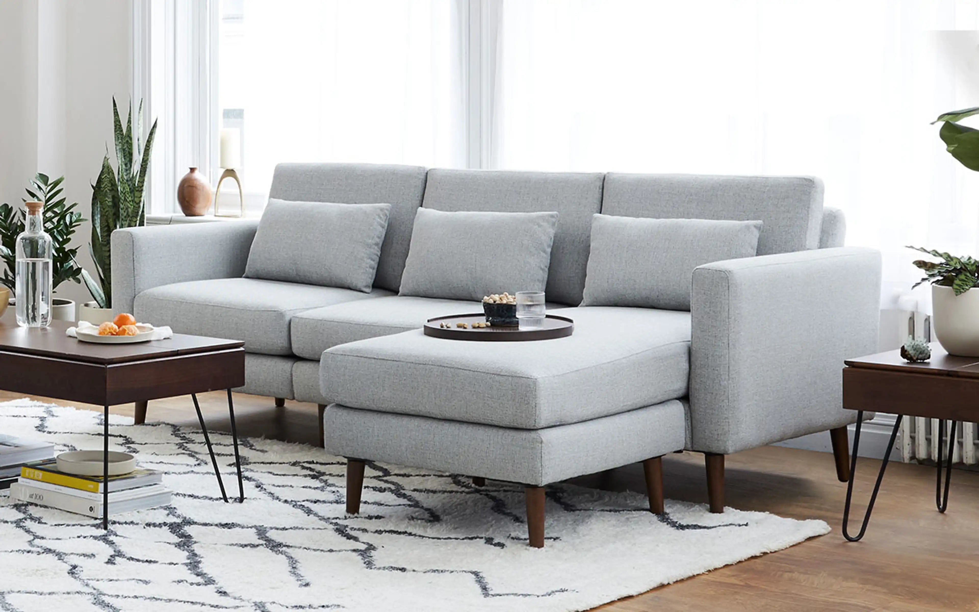 modern light gray sectional sofa with chaise lounge and matching ottoman on white rug in living room