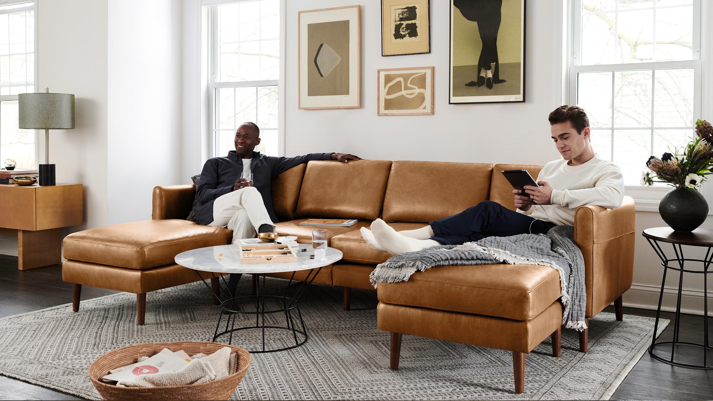 two men lounging on a burrow u_shaped sofa