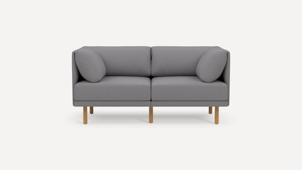 Modern two-seater sofa with light gray fabric upholstery, rounded armrests, and wooden legs, shown on white background.
