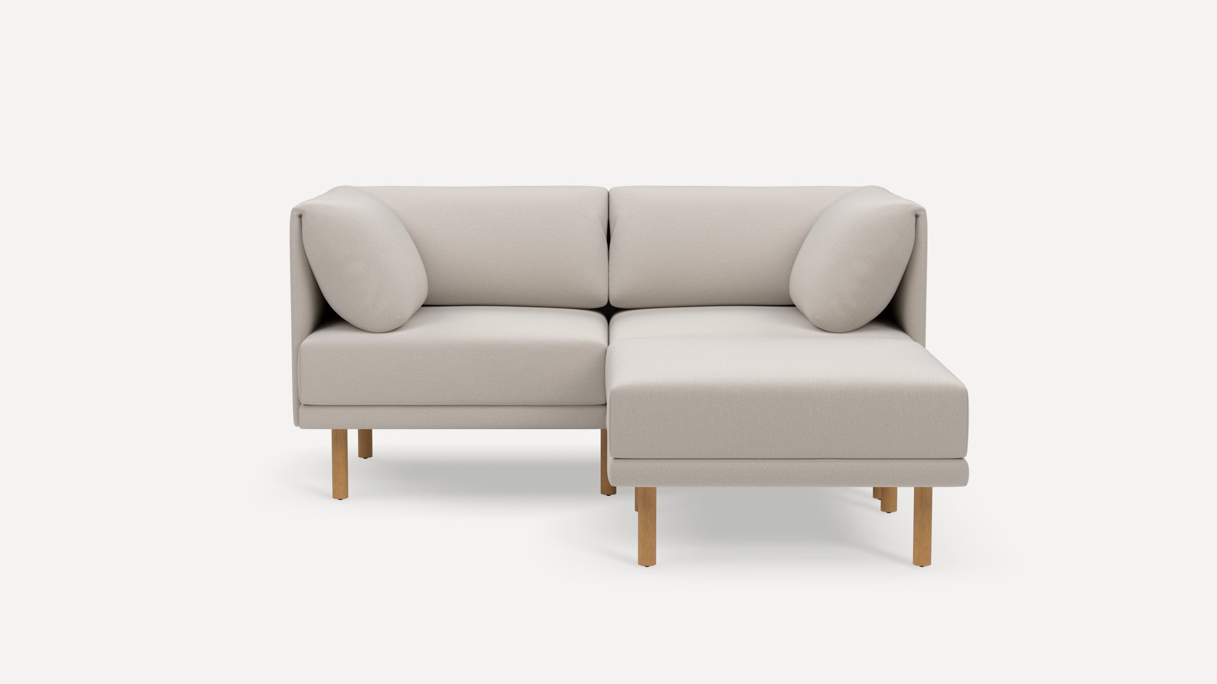 Light beige modern sectional sofa with wooden legs, two back cushions, and a right chaise lounge on a white background.