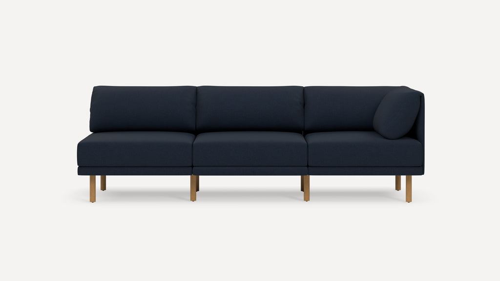 Modern navy blue three-seater sofa with wooden legs, featuring a right-side armrest and cushioned backrest and seat.