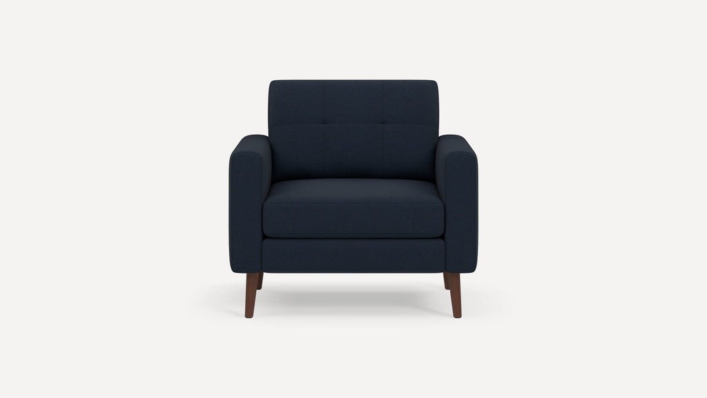 Dark navy blue upholstered armchair with tufted backrest and wooden tapered legs, shown against a plain white background.