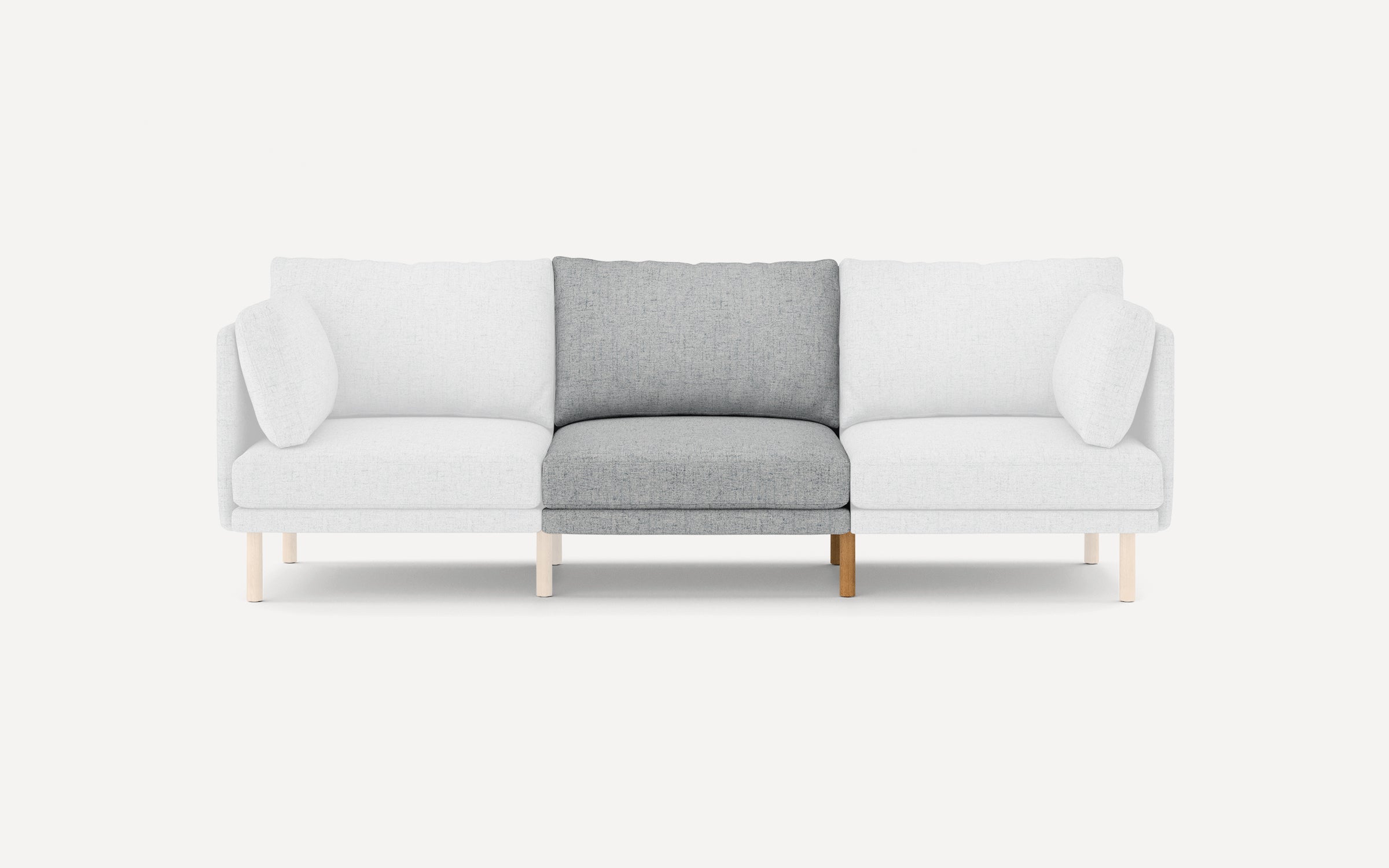Modern three-seater sofa with light wooden legs, white cushions on sides, and a contrasting light gray cushion in the center.